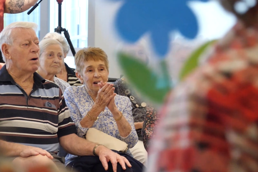 two elderly people sitting and clapping