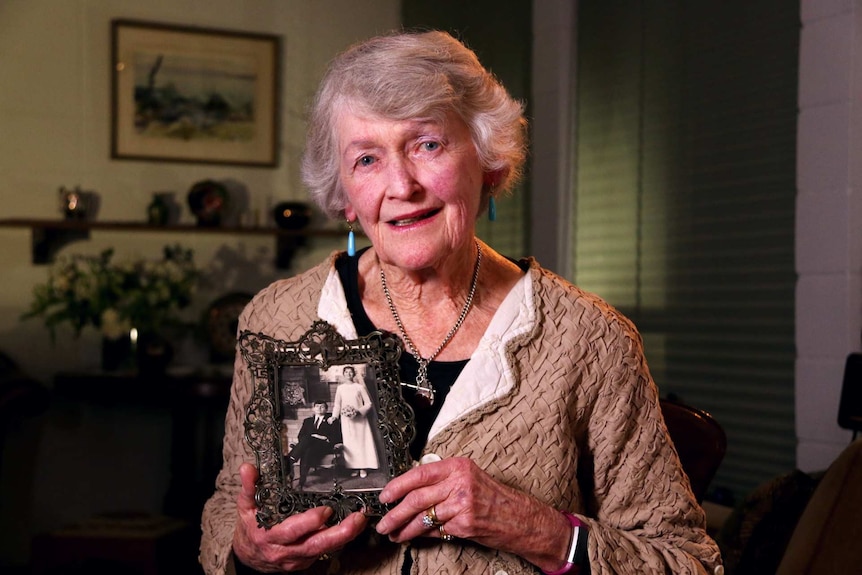 Wendy Saclier holds a framed black-and-white wedding photo.