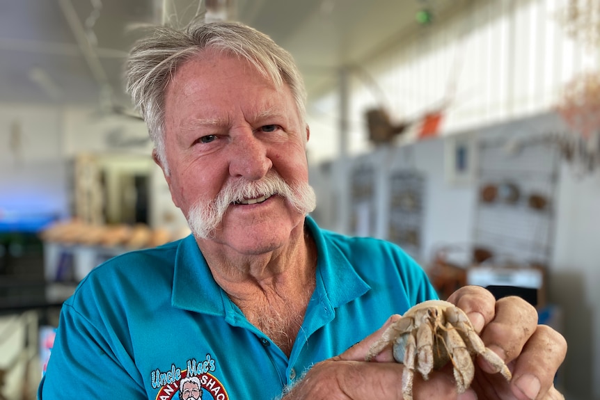 Merv Cooper holds a hermit crab to the camera.