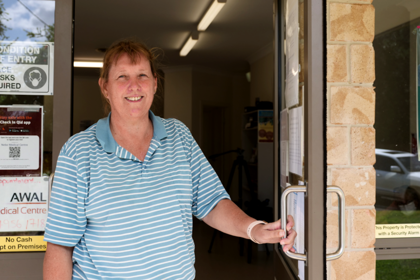 A woman stands in a doorway and smiles at the camera.