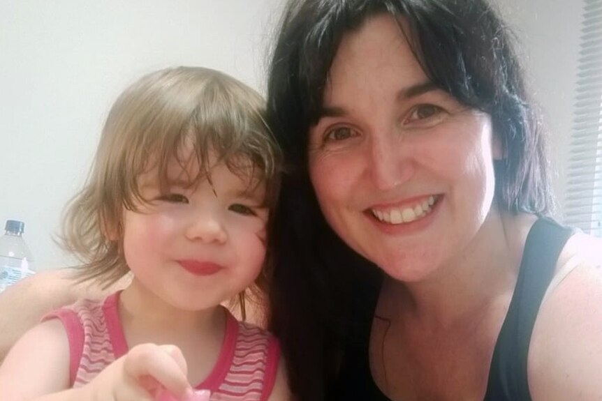 A woman with dark hair and her young daughter pose for a selfie
