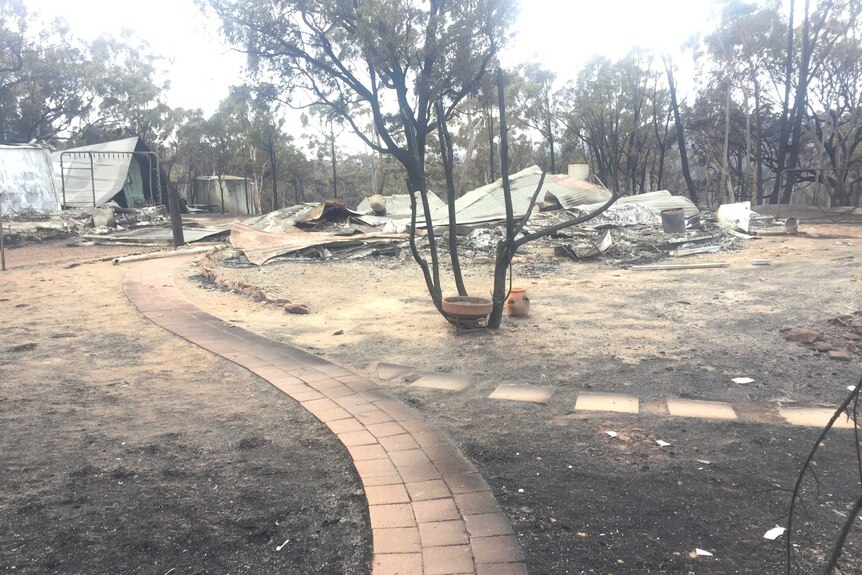 A house in bush at Carwoola in NSW is reduced to rubble and twisted tin by a bushfire.