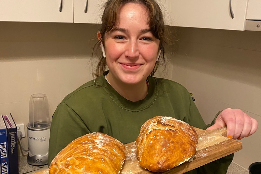 Emma Edwards holding a bread board with two loaves on it