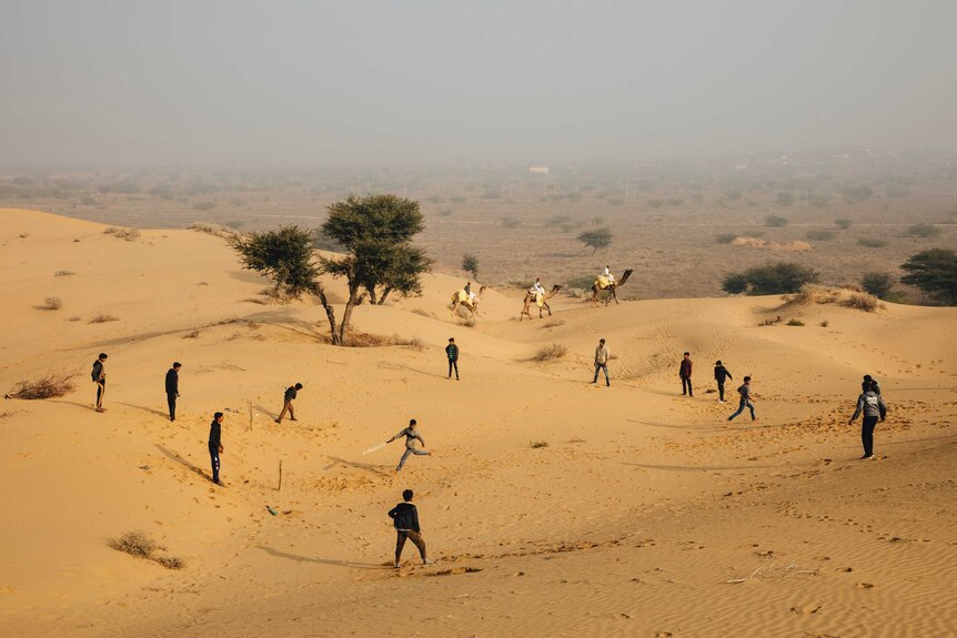 People play cricket on sand dunes.
