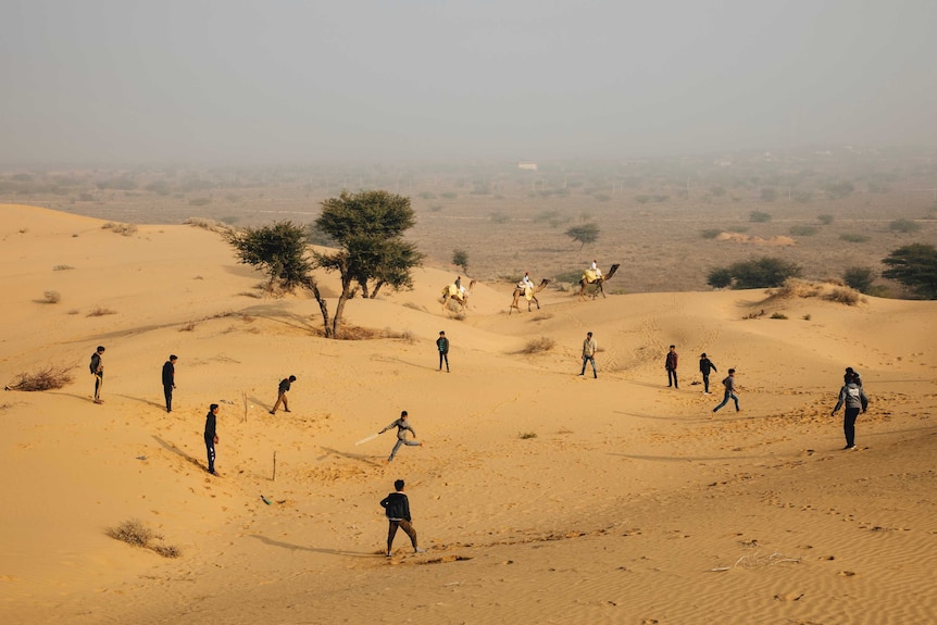 People play cricket on sand dunes.