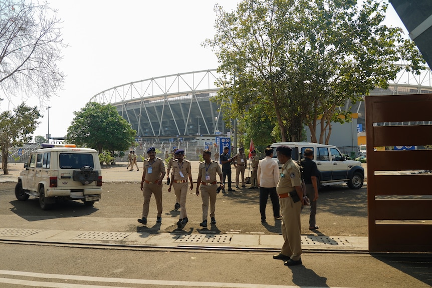 A group of security officers walk near a large sporting stadium