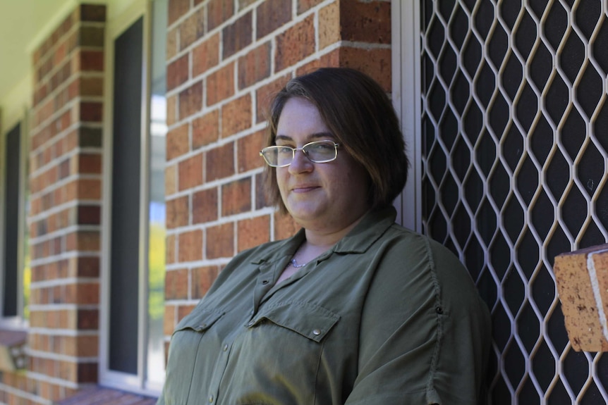 Woman in green shirt and glasses staring at camera.