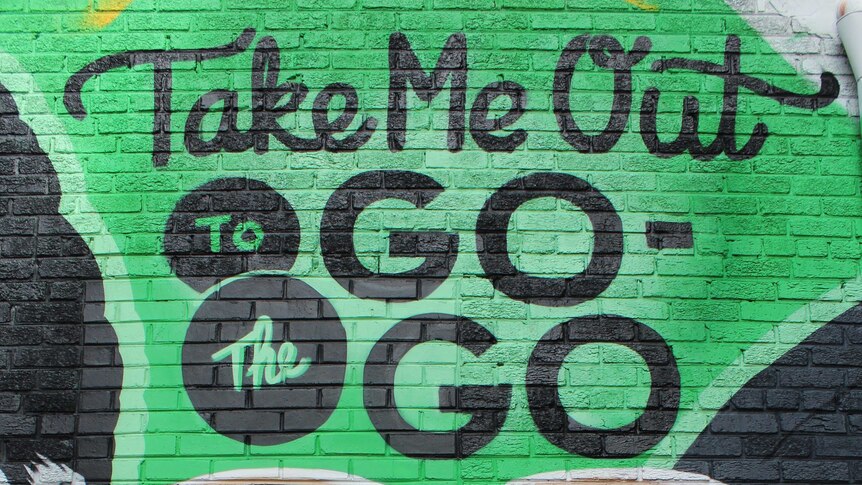 A green mural with the text "take me out to the go-go"