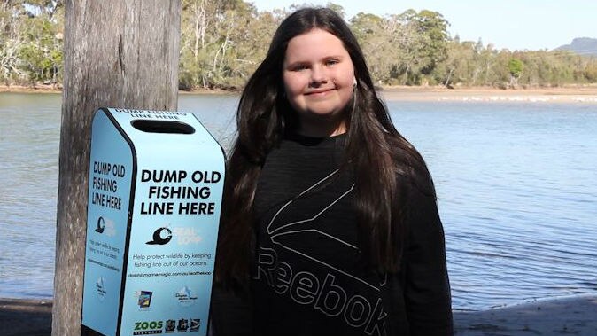 Young girl stands beside the small fishing line bin attached to a pole with a small opening to stop scavenger birds entering