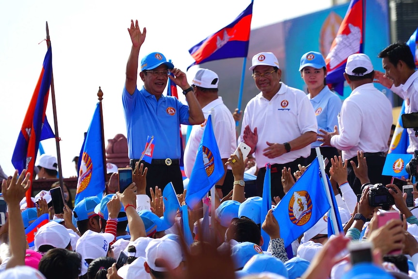 Cambodian Prime Minister raises his left hand to wave to a crowd