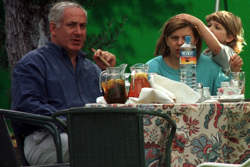 A family sit around a table with their son, who has his hand on his mother's head