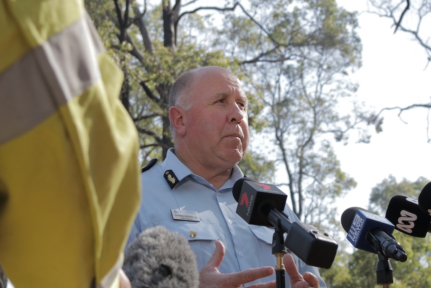 A low shot of a man speaking to media in a forest