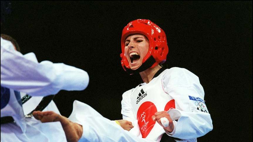 Lauren Burns, on 27 September 2000, pictured while striking her opponent with her foot. She is yelling mid-strike.