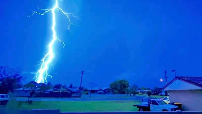 A huge lightning strike over suburbia at night time.