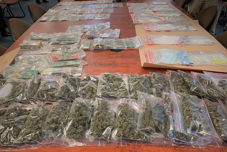 Drugs, cash and other items seized by Tasmania Police displayed on a table.