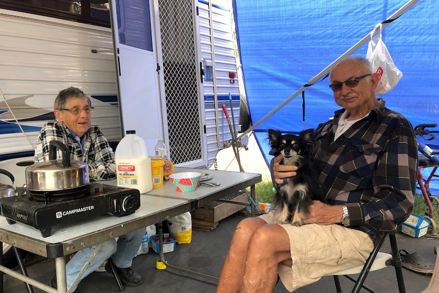 An older couple sit at their camping table for breakfast beside their caravan in Moura