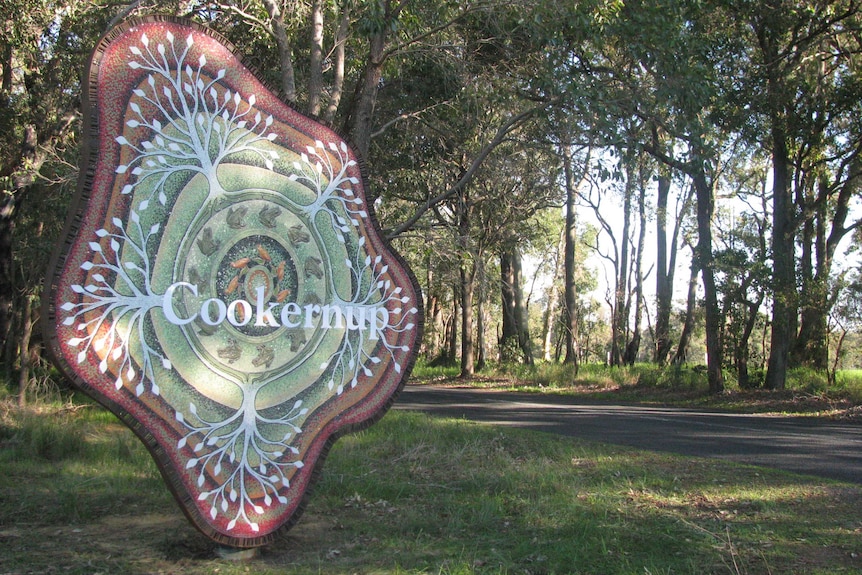 Large entry statement for town of Cookernup beside a road and trees