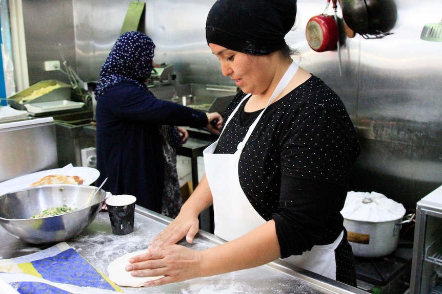 Refugee Gulsum Haider cooks Afghan food in a kitchen