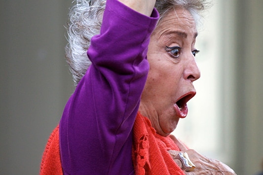 Spanish mezzo-soprano Teresa Berganza with her hand raised in the air, her face animated.