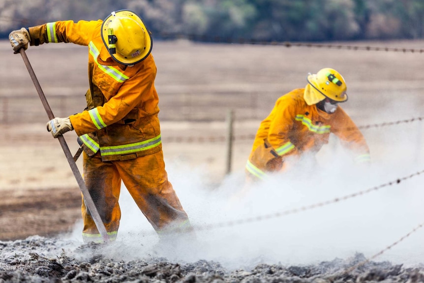 CFA volunteers cool and turnover the earth which is still burning.