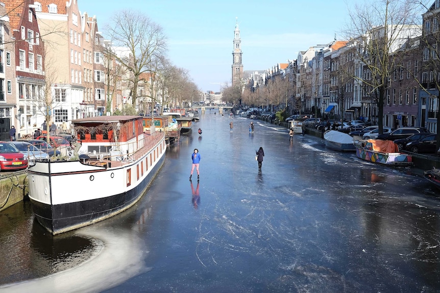People walk and skate on the frozen Prinsengracht canal in downtown Amsterdam.