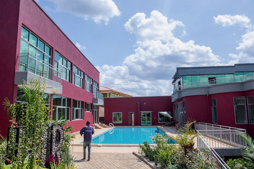 Un homme se tient près d'une piscine entourée de bâtiments 