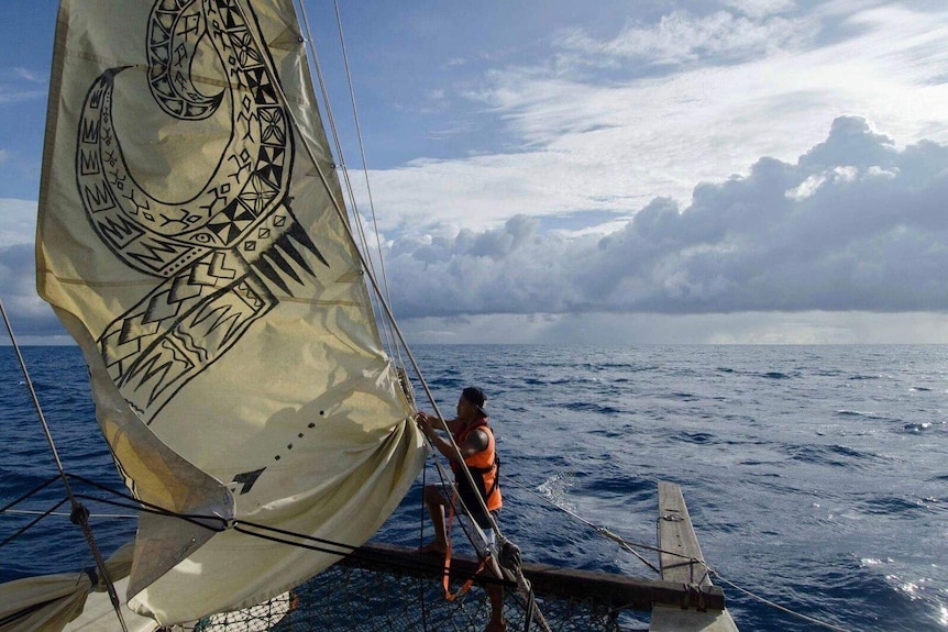 A crew member checks the boat's sails while at sea.