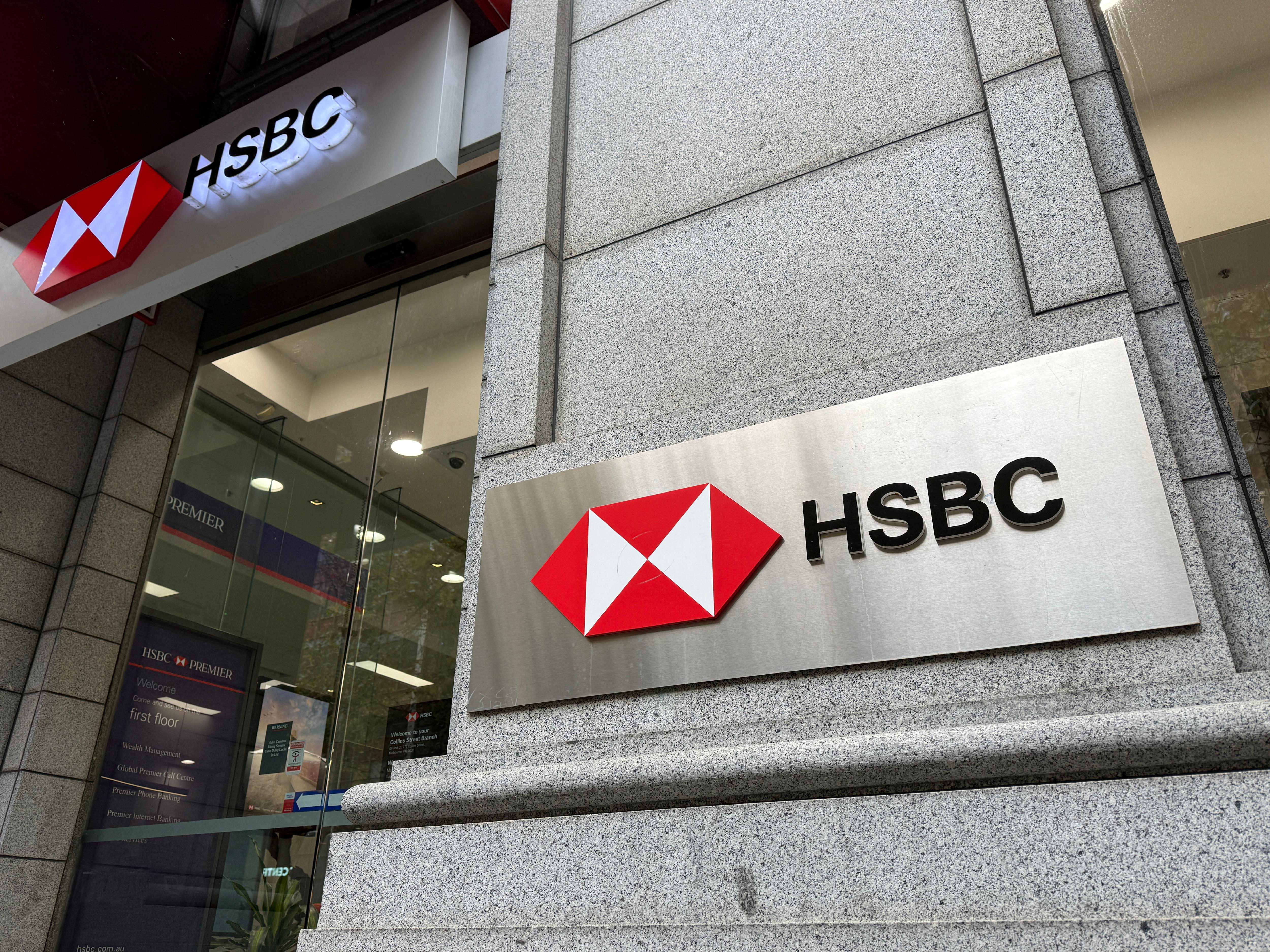 The exterior of a grey brick building with signage reading HSBC next to a red and white logo made up of diamonds.