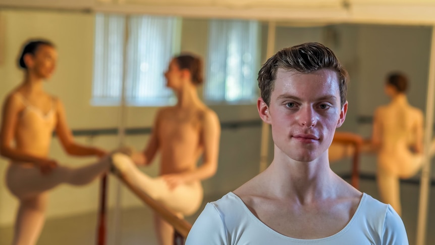 A young male ballet dancer stares at the camera.