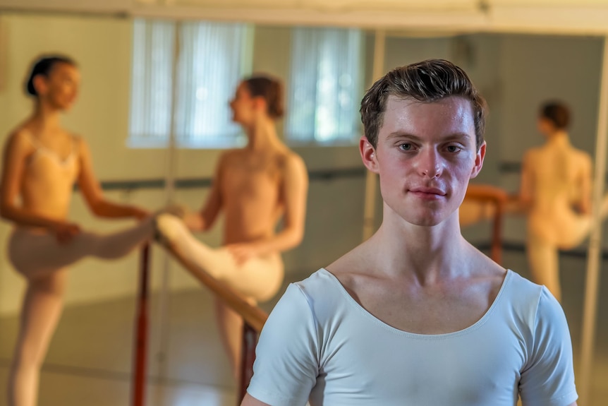 A young male ballet dancer stares at the camera.