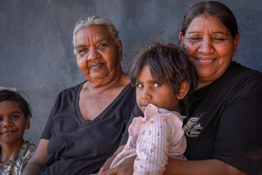 Two Aboriginal women sit with two little girls