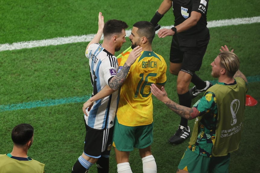 Messi has his arm around Behich, patting him on the back as referees watch on. 