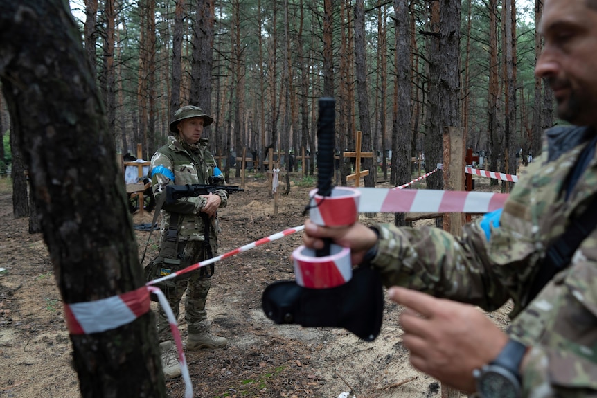 Officials inspect unidentified graves of civilians and Ukrainian soldiers.