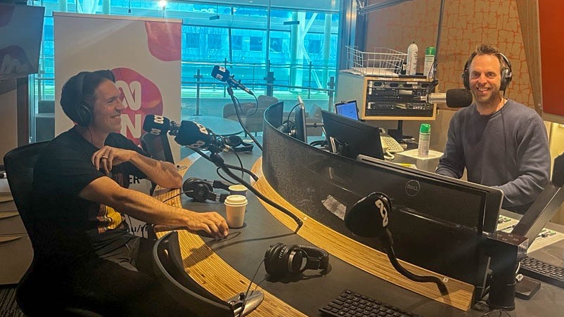 Ben Shewry and Hugh van Cuylenburg smiling in front of microphones in a radio studio