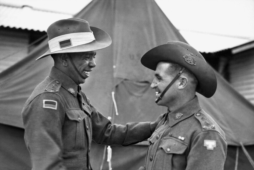 Two men in military uniforms shake hands.
