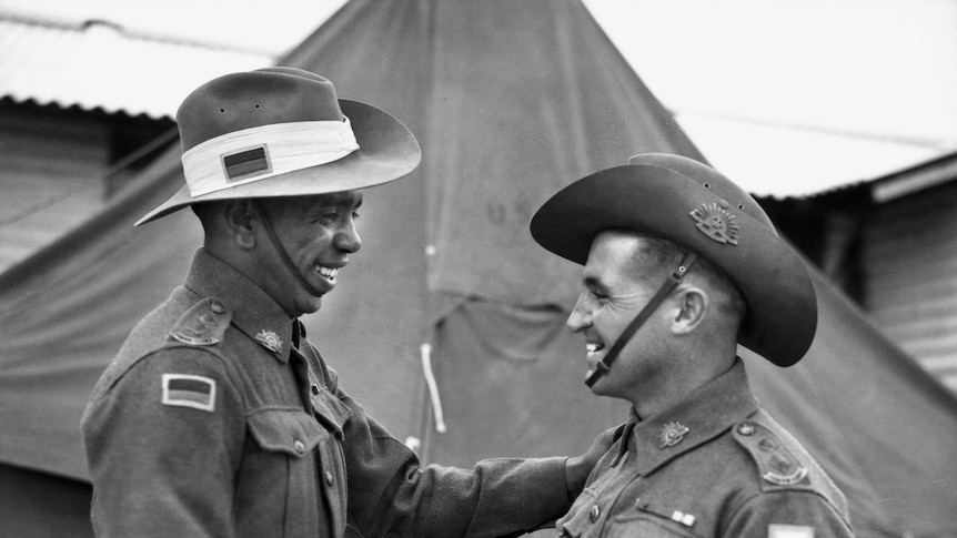 Two men in military uniforms shake hands.