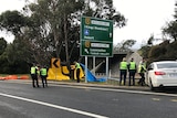 Police standing near tarpaulins erected at crash site on Tasmanian highway.