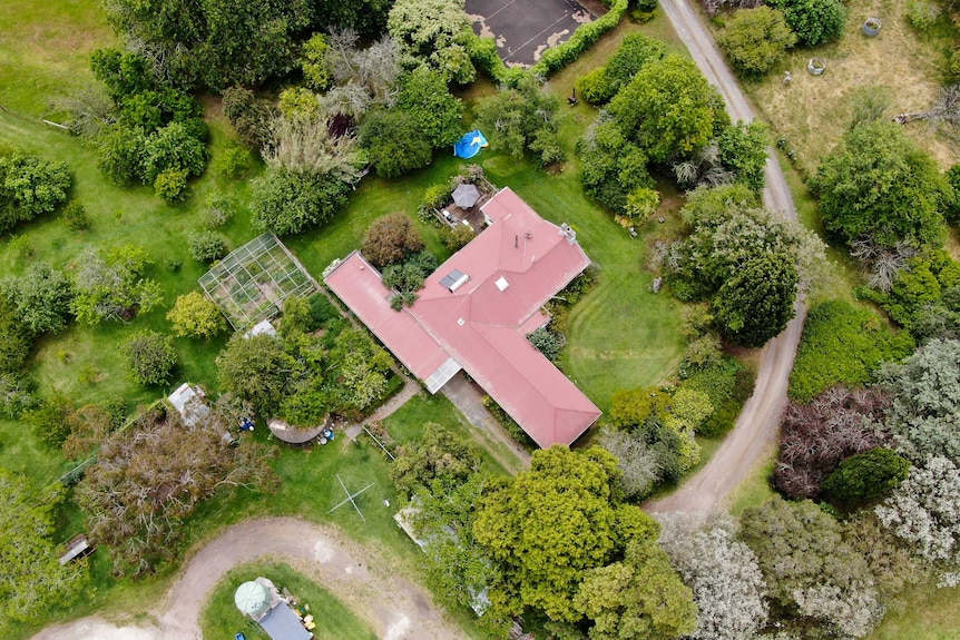 A drone shot shows many large green trees, a greenhouse, tennis court and farm appliances surrounding the Bokensha home.