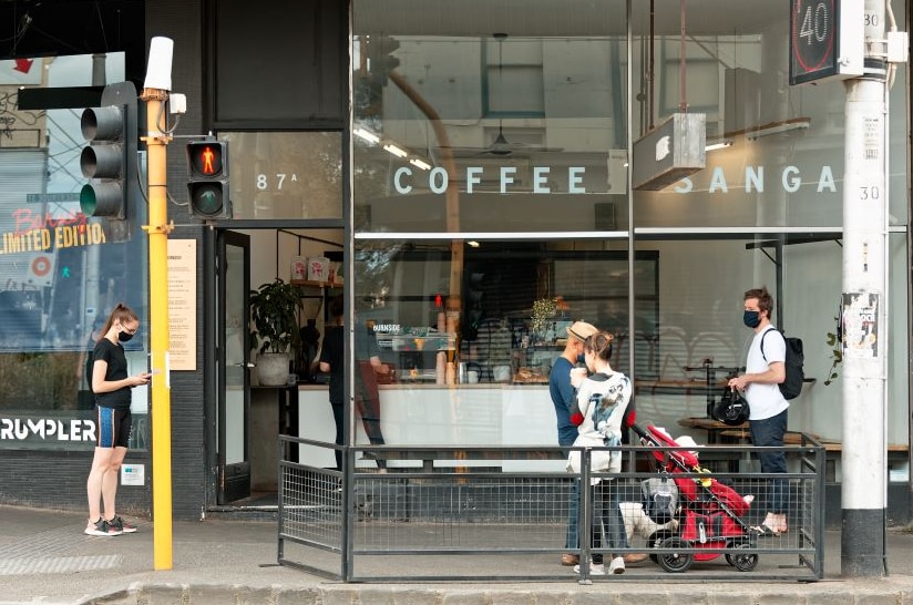 Four people wait outside a cafe in inner Melbourne.