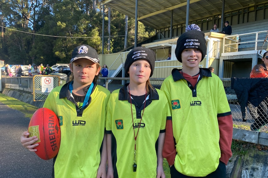 Three young brothers in their football umpiring gear standing in a line. 