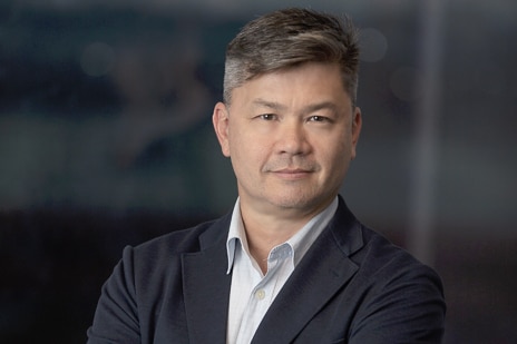 Portrait on a man, Dr Alan Pearce, in a suit with a blurred background behind.