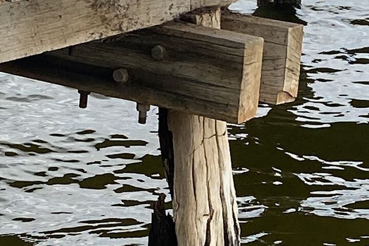 A wooden post holding up a jetty has snapped in the water.