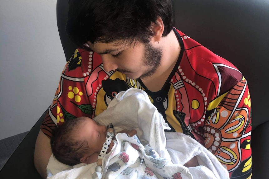 A father holding his son in hospital