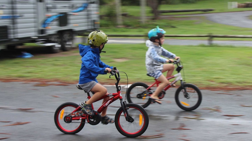 Two boys riding bikes in a caravan park