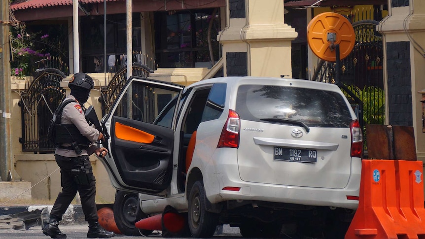 Polisi bersenjata memeriksa sebuah mobil.