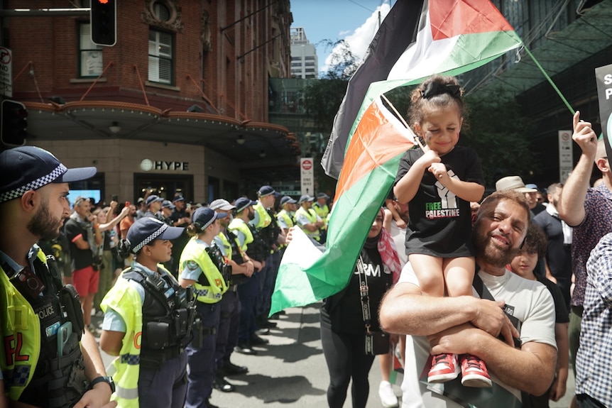 Pro-Palestinian protester carries a young girl on shoulders while marching through CBD