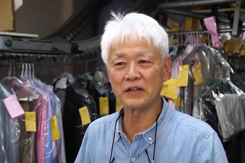 an elderly asian man in a dry cleaners