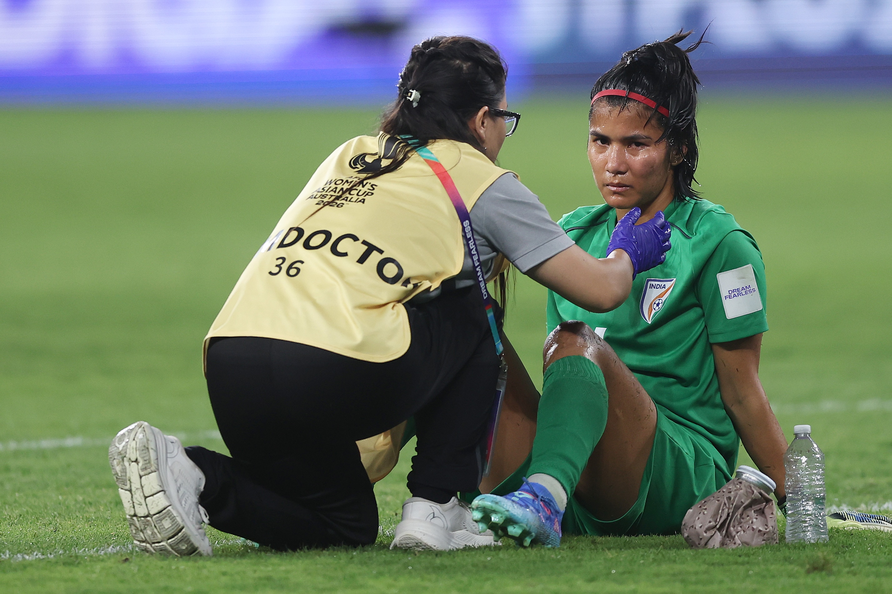 Um goleiro de verde recebe tratamento para uma maçã do rosto inchada