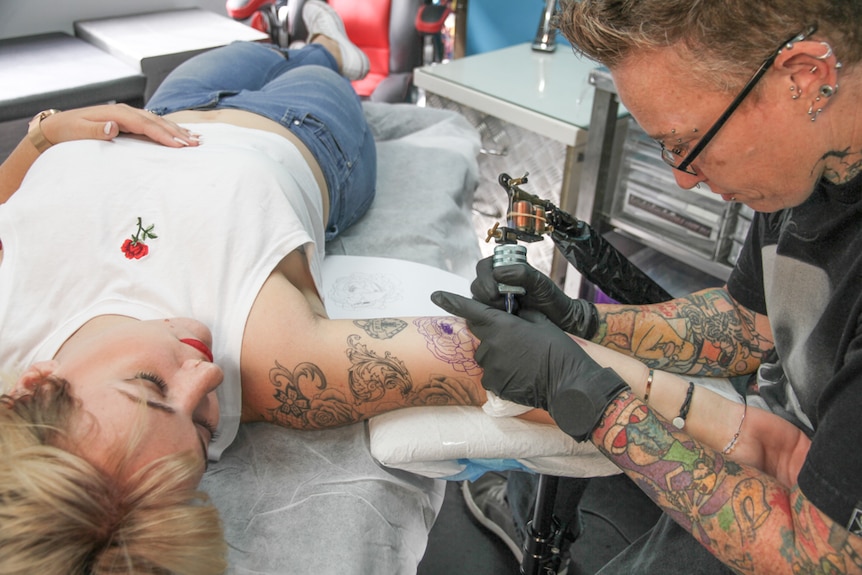Rae Shiels adds another rose tattoo to Alicia Wasley''s arm as a part of the growing sleeve she is creating.