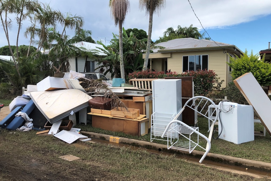 Flood damaged furniture lining the kerb in front of a house.